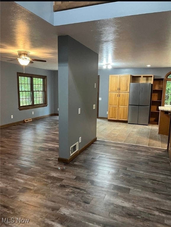 interior space featuring ceiling fan, dark wood-type flooring, and a textured ceiling