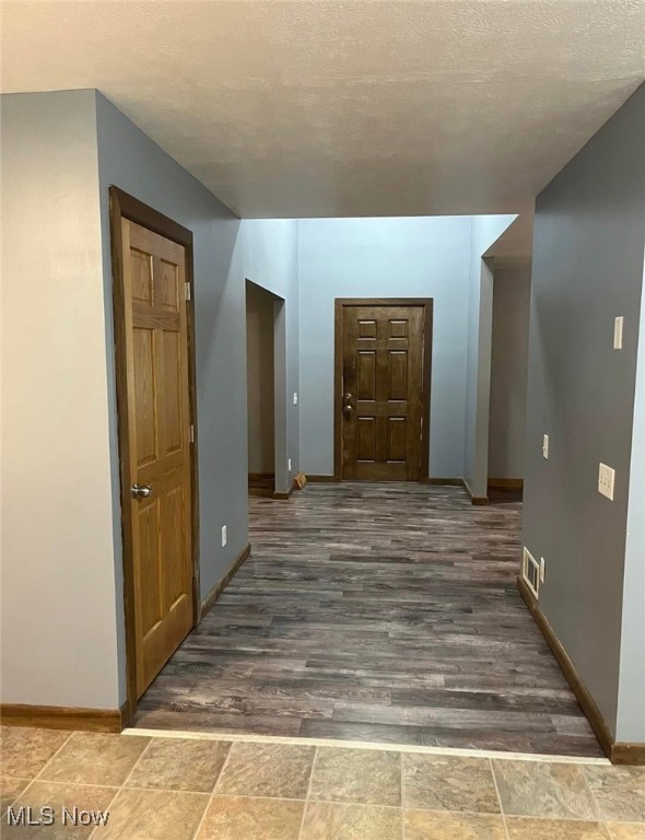 hallway with dark hardwood / wood-style floors and a textured ceiling