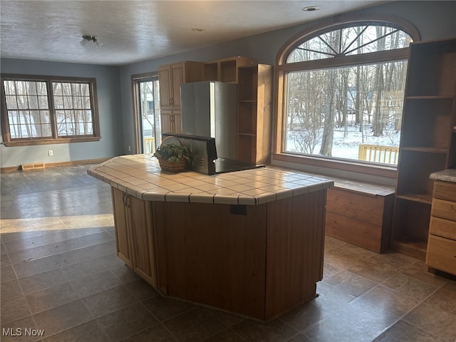 kitchen featuring tile counters, a kitchen island, and a textured ceiling