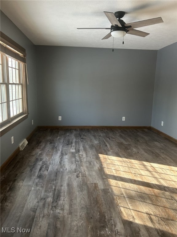 empty room featuring a textured ceiling, dark hardwood / wood-style floors, and ceiling fan