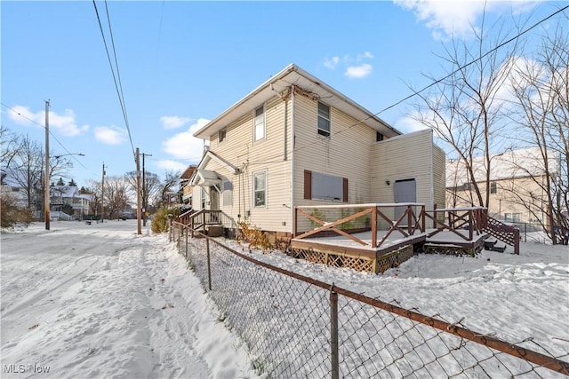 snow covered house featuring a deck, crawl space, and fence