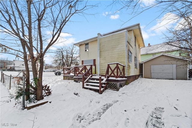 view of snowy exterior with a garage and an outbuilding