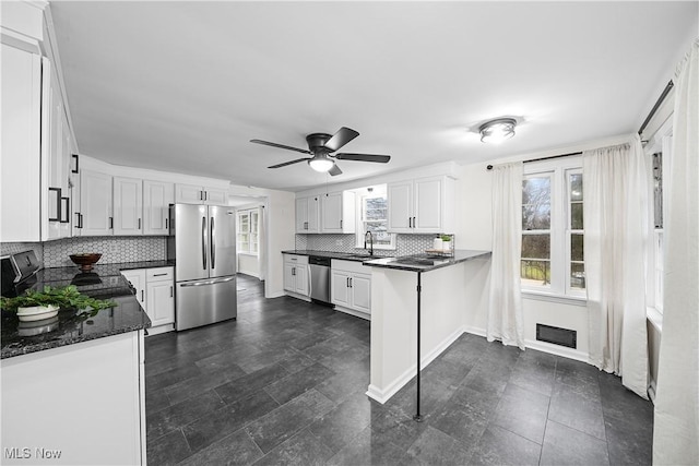 kitchen featuring white cabinets, appliances with stainless steel finishes, decorative backsplash, and ceiling fan