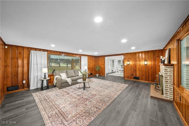 living room featuring wood walls, plenty of natural light, and dark wood-type flooring