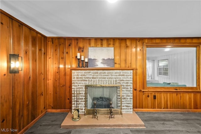 living room with a fireplace, dark wood-type flooring, and wood walls