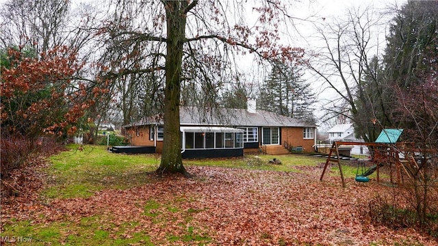 rear view of house with a playground and a sunroom