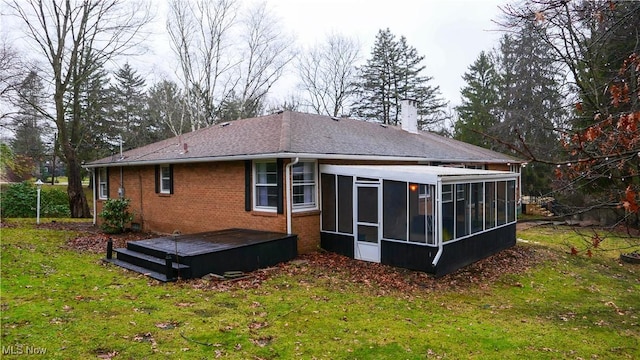 rear view of house featuring a sunroom and a lawn