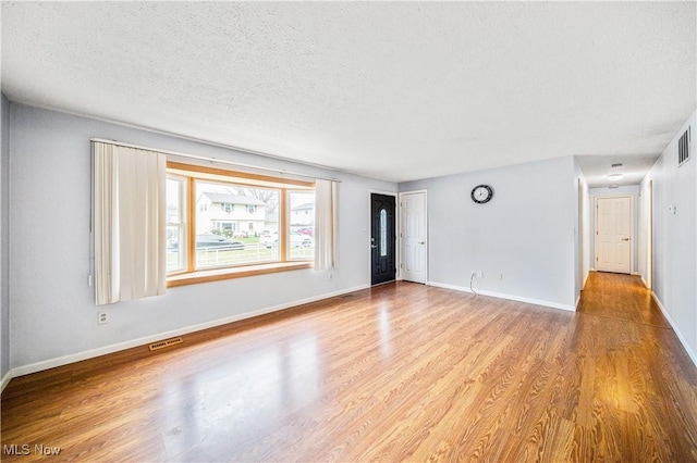 empty room with light hardwood / wood-style flooring and a textured ceiling