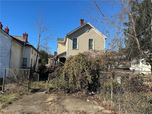 view of front of house featuring a chimney and fence