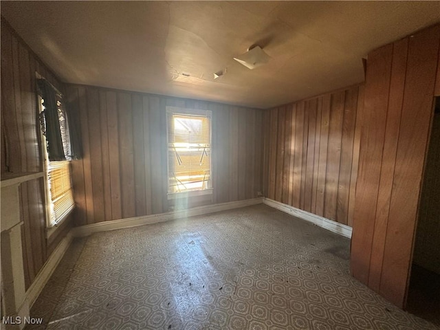 unfurnished room featuring wood walls and baseboards