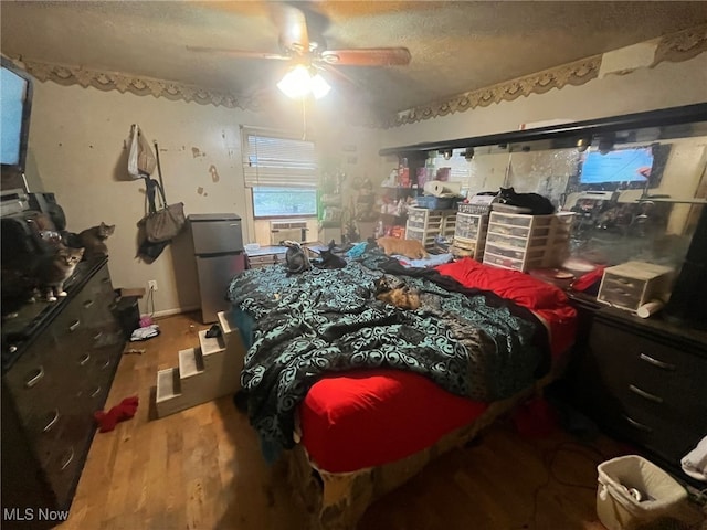 bedroom featuring hardwood / wood-style floors, refrigerator, a textured ceiling, and ceiling fan