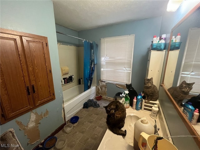 bathroom with shower / bathtub combination with curtain and a textured ceiling