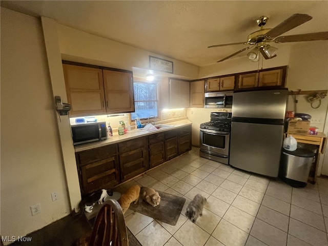 kitchen featuring ceiling fan, sink, light tile patterned floors, and appliances with stainless steel finishes