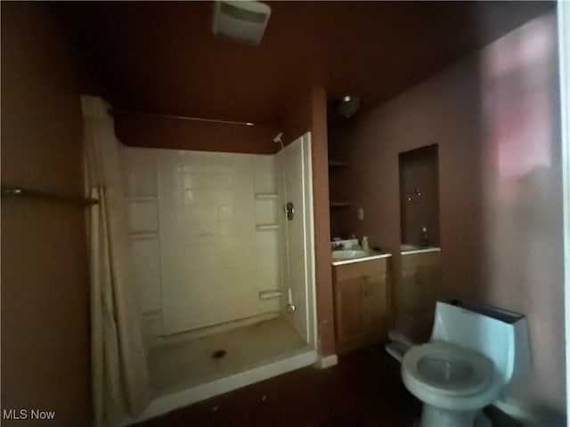 bathroom featuring toilet, vanity, and walk in shower