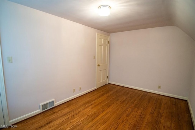 unfurnished room with hardwood / wood-style flooring and lofted ceiling