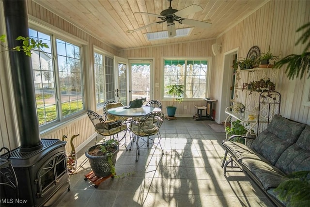 sunroom / solarium with wooden ceiling, ceiling fan, a wood stove, and lofted ceiling