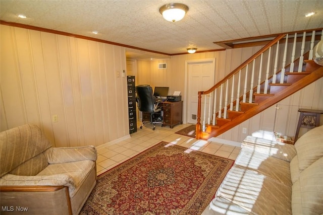 living room with wooden walls, light tile patterned floors, a textured ceiling, and ornamental molding