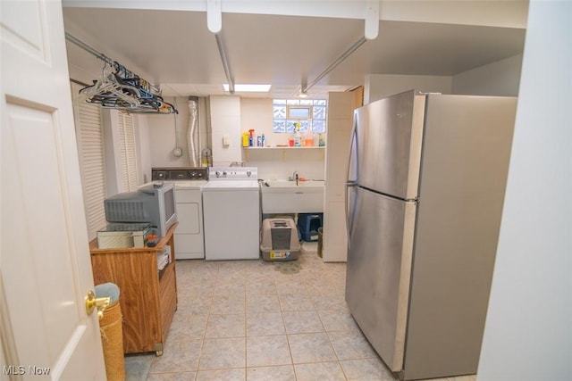 laundry area featuring light tile patterned flooring, sink, and washing machine and clothes dryer