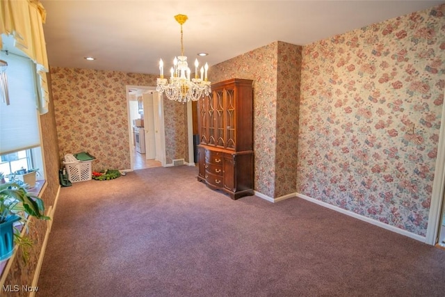 spare room with dark carpet and an inviting chandelier