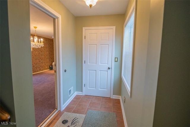 entryway featuring carpet floors and a chandelier