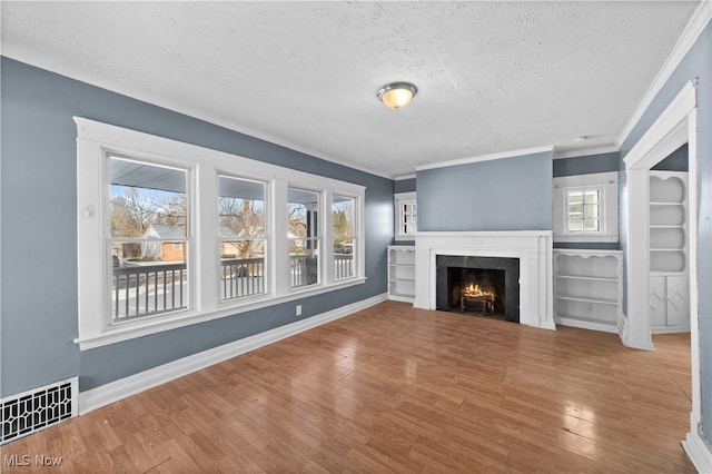 unfurnished living room with crown molding, hardwood / wood-style floors, a healthy amount of sunlight, and a textured ceiling