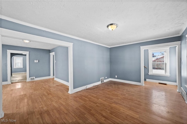 unfurnished room featuring wood-type flooring, a textured ceiling, and ornamental molding