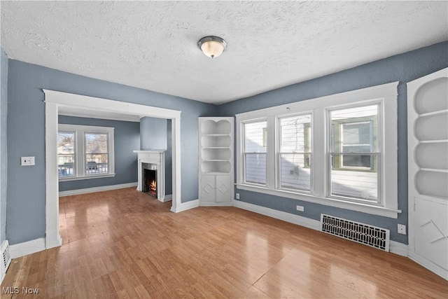 unfurnished living room featuring hardwood / wood-style floors and a textured ceiling