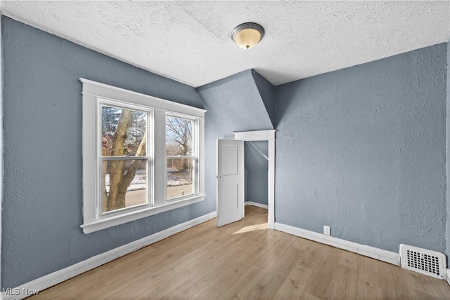 bonus room with a textured ceiling, wood-type flooring, and lofted ceiling