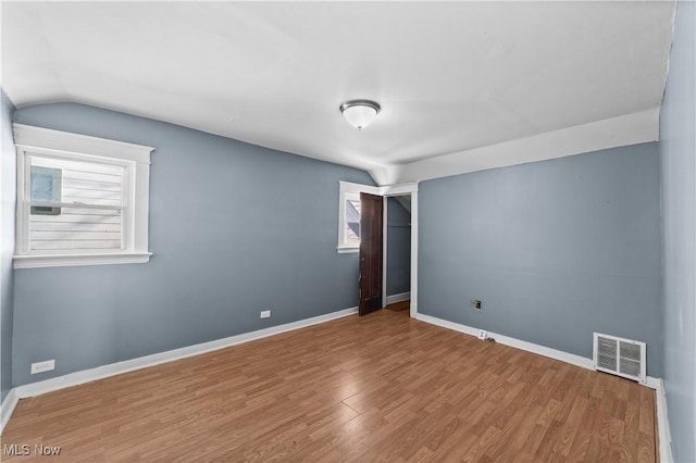 unfurnished room with hardwood / wood-style floors and vaulted ceiling