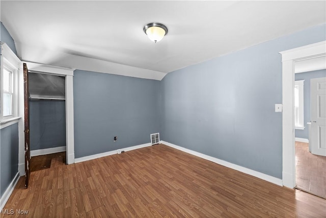 unfurnished bedroom featuring hardwood / wood-style floors, a closet, and lofted ceiling