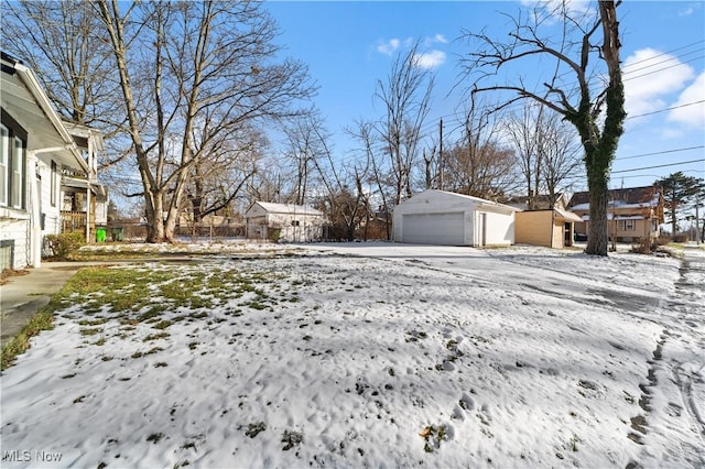 yard layered in snow with an outbuilding and a garage