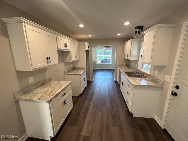 kitchen featuring light stone counters, ceiling fan, dark wood-type flooring, sink, and white cabinetry