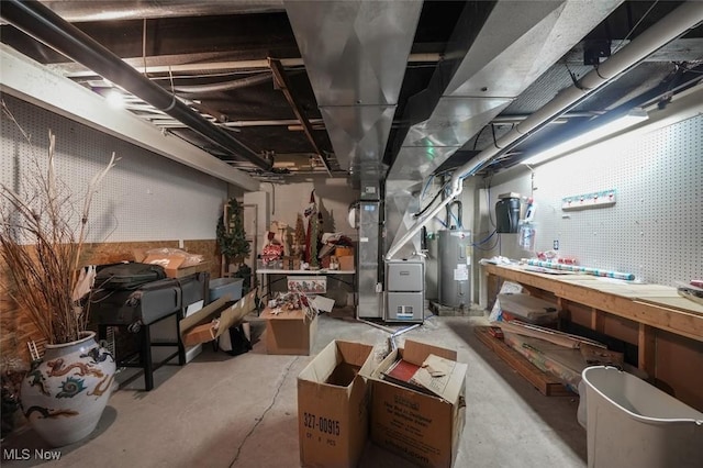 basement featuring a workshop area, electric water heater, and heating unit