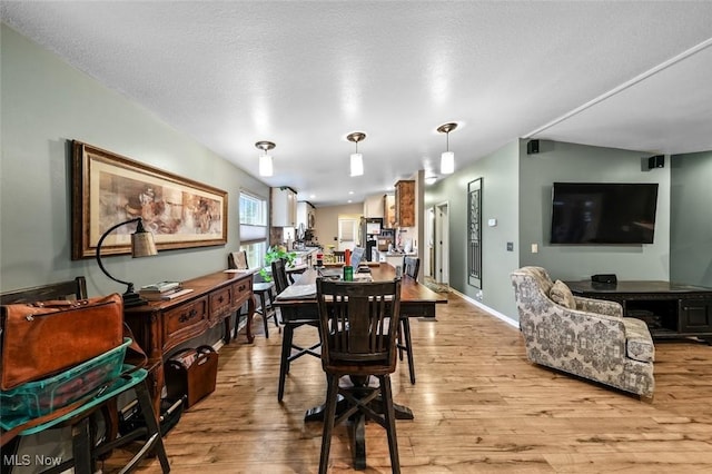 dining area with a textured ceiling and light hardwood / wood-style flooring