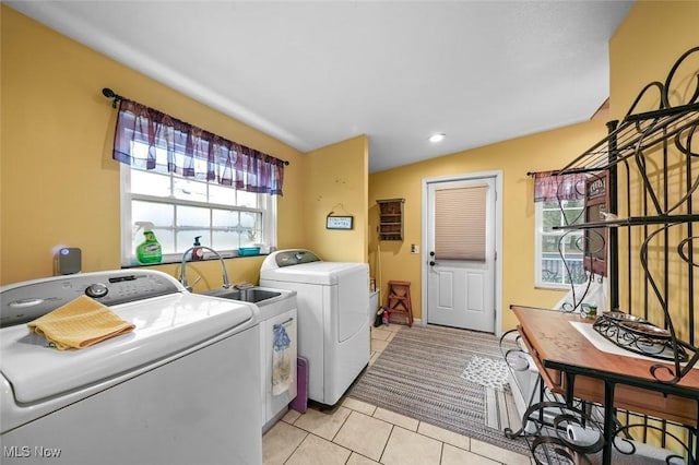 laundry area with plenty of natural light, light tile patterned flooring, sink, and washing machine and clothes dryer