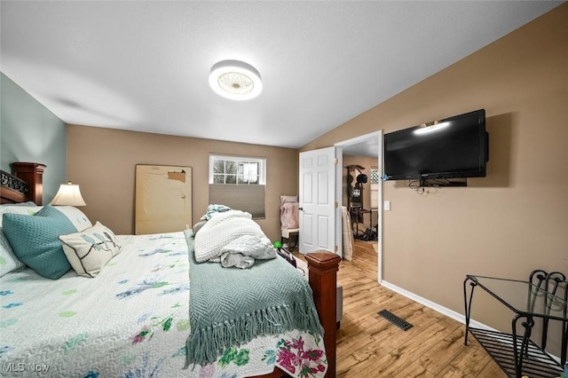 bedroom with vaulted ceiling and hardwood / wood-style flooring