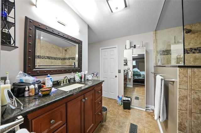 bathroom with tile patterned flooring, vanity, and tiled shower