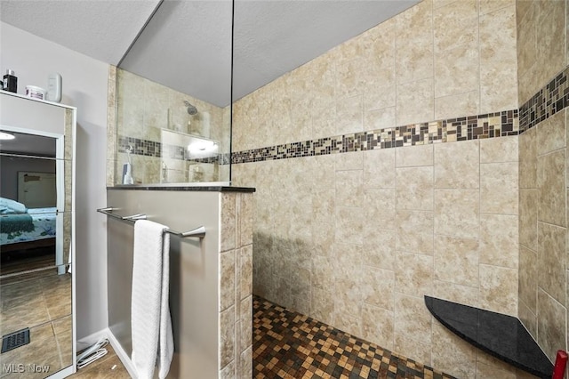 bathroom featuring a textured ceiling and tiled shower