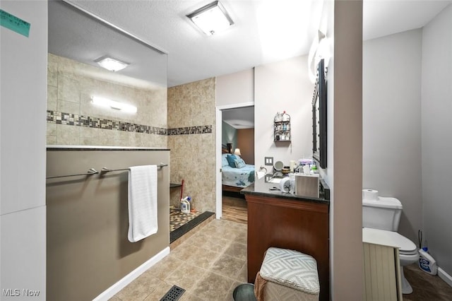 bathroom featuring tile patterned flooring, toilet, and a tile shower