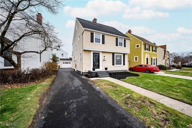 view of front of house featuring a garage, an outdoor structure, and a front yard