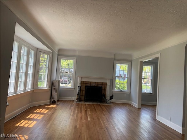 unfurnished living room with a fireplace, dark wood-type flooring, a textured ceiling, and radiator heating unit