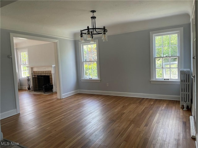 unfurnished living room featuring a notable chandelier, plenty of natural light, and dark hardwood / wood-style floors