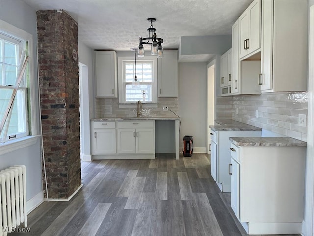 kitchen featuring white cabinets, plenty of natural light, and radiator