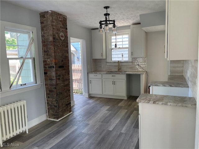 kitchen with radiator, white cabinetry, sink, dark wood-type flooring, and pendant lighting