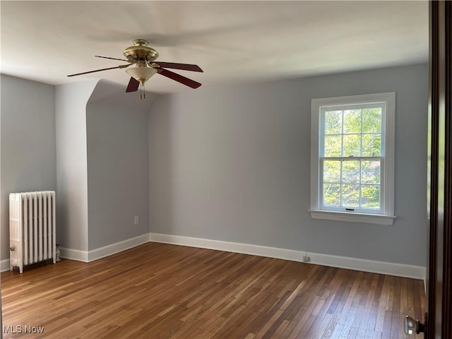 spare room featuring ceiling fan, wood-type flooring, and radiator