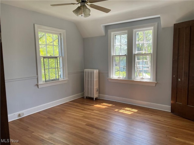 additional living space with hardwood / wood-style flooring, lofted ceiling, ceiling fan, and radiator heating unit