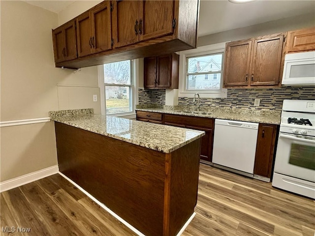 kitchen featuring kitchen peninsula, light wood-type flooring, white appliances, and sink