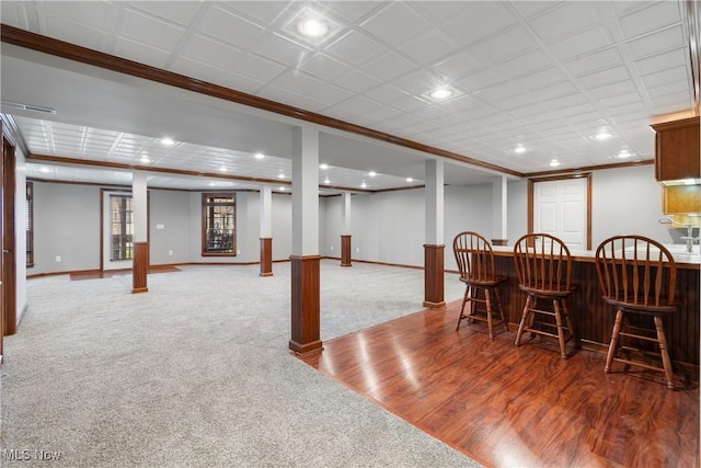 dining space with bar area, wood-type flooring, and crown molding