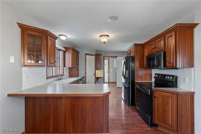 kitchen featuring sink, kitchen peninsula, stainless steel appliances, and dark wood-type flooring