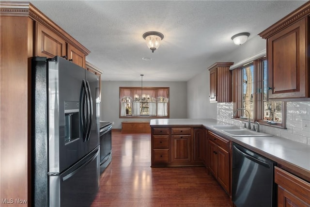 kitchen with kitchen peninsula, stainless steel appliances, dark wood-type flooring, sink, and a notable chandelier